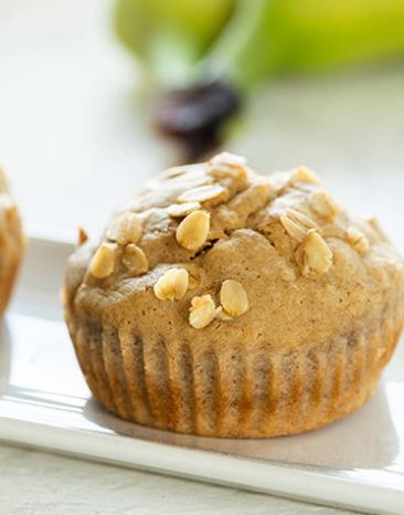 Zwei Bananenmuffins mit Ahornsirup auf einer Servierplatte.