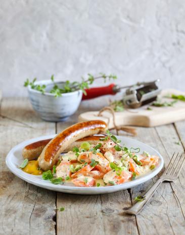 Bratwurst mit Rahm-Karotten auf einem Teller.