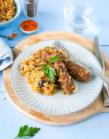 Ein Teller, angerichtet mit Cevapcici und Gemüsereis.