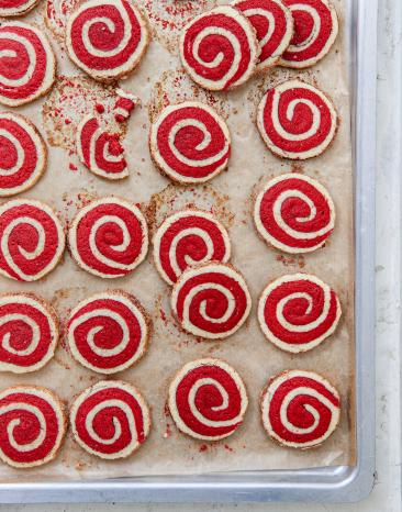 Mehrere Dinkel Zimtschnecken-Kekse rot-weiß auf einem Backblech.