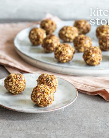 Mehrere Energiekugeln mit Datteln und Honig auf zwei Tellern.