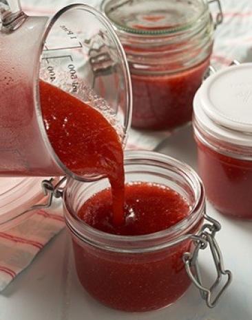 Gläschen, die mit Erdbeer-Rhabarber-Konfitüre befüllt werden