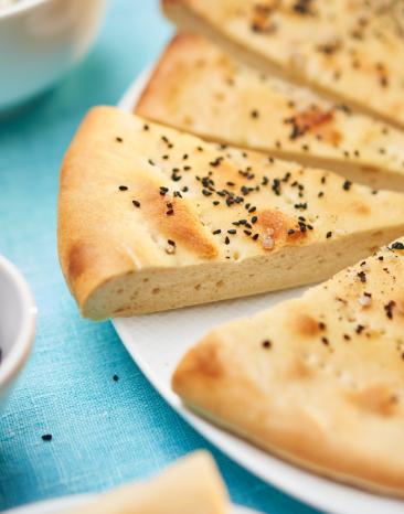 Fladenbrot türkischer Art mit Schwarzkümmel und Pfeffer in Stücke geschnitten auf einem Teller.