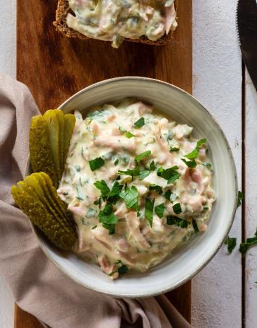 Brett mit belegten Broten und Fleischsalat in Schälchen