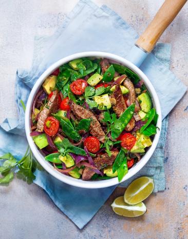 Gebratene Rinderfiletstreifen mit Tomaten und Zuckerschoten in einem tiefen Teller angerichtet.