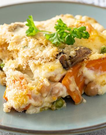 Ein Stück Gemüseauflauf mit Pilzen auf einem Teller.