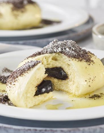 Germknödel mit Mohn-Butter angeschnitten auf einem Teller. Germknödel mit Mohn-Butter angeschnitten auf einem Teller.