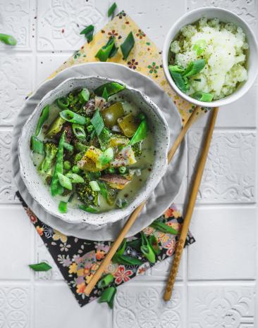 Grünes Kokos-Gemüse-Curry mit Blumenkohlreis in einem Teller.