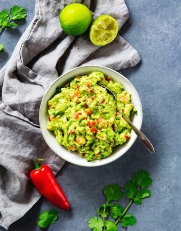 Guacamole in Schüssel, Tuch, Limette und Chilischote