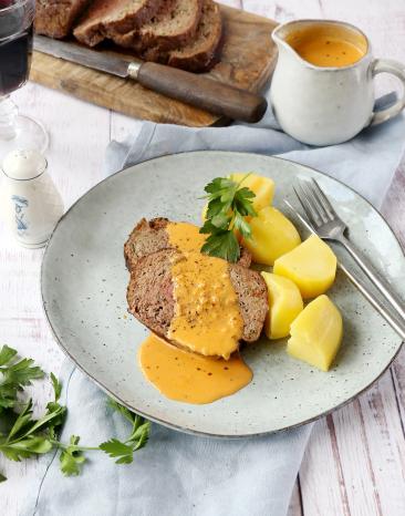 Hackbraten mit roter Soße und Kartoffeln auf einem Teller. Hackbraten mit roter Soße und Kartoffeln auf einem Teller.