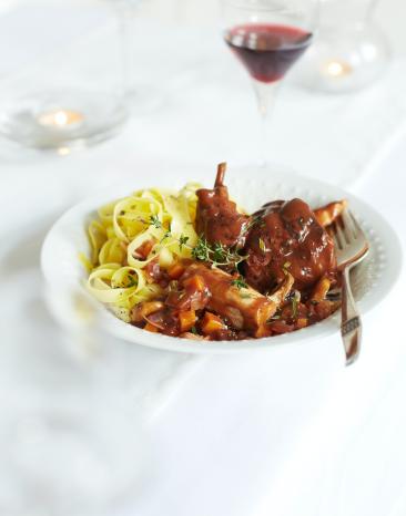 Nudeln und Kaninchenfleisch in einer Schüssel mit Sauce. 