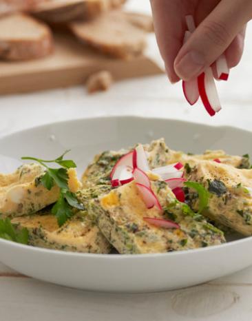 Käse-Kräuter-Omelett in Stücken mit Radieschen in einem Teller.