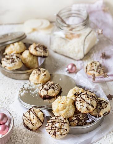 Kokosmakronen im Bild verteilt mit vielen Kokosraspeln und Schokoladenglasur beträufelt .