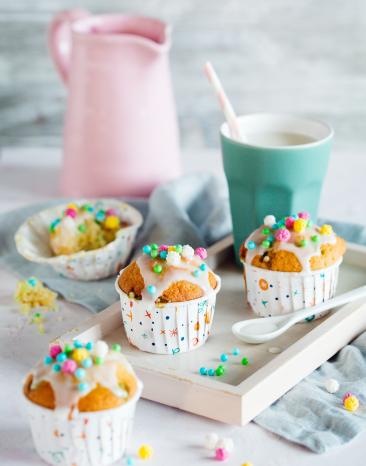 Vier Konfetti-Muffins mit bunten Streuseln