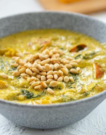 Kürbis mit Pesto und gerösteten Pinienkernen in einer Schale.