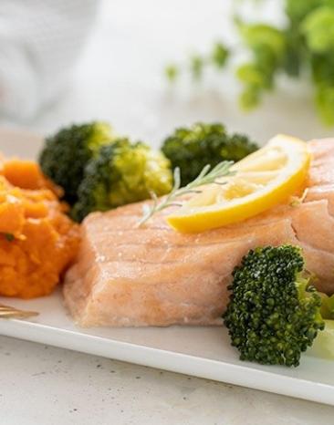 Lachs, gedämpft mit Süßkartoffelpüree und Brokkoli auf einem Teller angerichtet. Lachs, gedämpft mit Süßkartoffelpüree und Brokkoli auf einem Teller angerichtet.