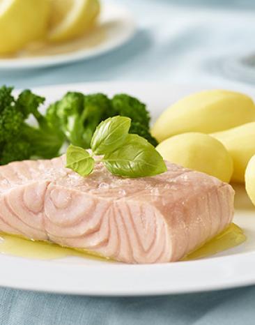 Lachsfilet gedämpft mit Brokkoli und Kartoffeln auf einem Teller.