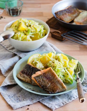 Lachsforelle auf Kartoffel-Spitzkohl-Gemüse auf zwei Tellern angerichtet.