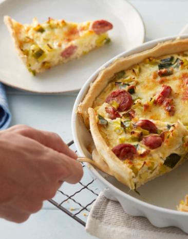 Ein Stück Lauchquiche wird aus einer Form gehoben.