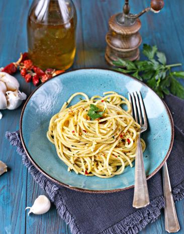 Spaghetti aglio, olio e peperoncino auf einem Teller auf einem gedeckten Tisch.