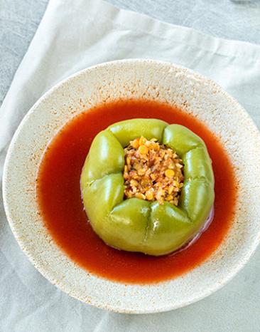 Paprikaschoten gefüllt mit Blumenkohl und Linsen auf Tomatensoße in einem Teller.