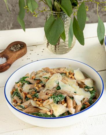 Penne mit Ziegenfrischkäse und Spinatsoße auf zwei Tellern angerichtet.