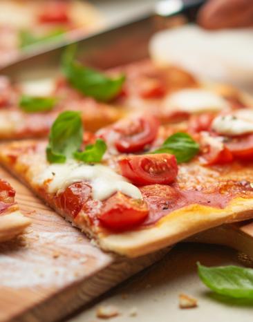 Pizza Margherita angeschnitten auf einem Holzbrett. Pizza Margherita angeschnitten auf einem Holzbrett.