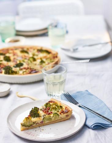 Quiche Lorraine mit Brokkoli als Stück auf einem Teller.