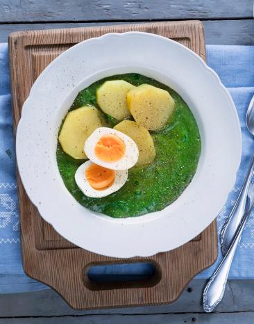 Rahmspinat mit Kartoffeln und Eiern auf einem Teller.