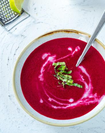 Rote-Bete-Kokos-Suppe mit Limette in einer Schale mit Löffel.
