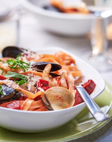 Rote Bete Tagliatelle mit Meeresfrüchten auf einem Teller angerichtet. Rote Bete Tagliatelle mit Meeresfrüchten auf einem Teller angerichtet.