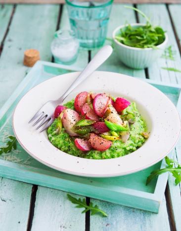 Rucolarisotto mit karamellisiertem Frühlingszwiebel-Radieschen-Gemüse in einem tiefen Teller angerichtet.