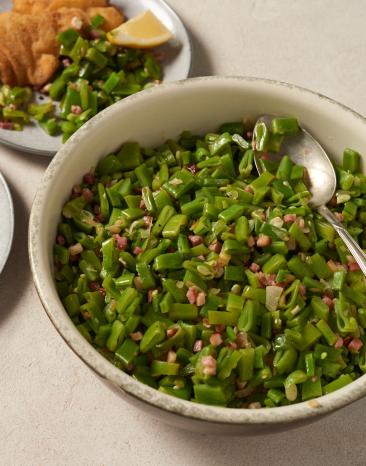 Salat mit grünen Bohnen in einer großen Schalen und auf einem Teller mit Schnitzel.
