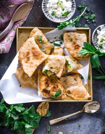 Samosas mit vegetarischer Füllung und Minz-Joghurt auf einem Teller Samosas mit vegetarischer Füllung und Minz-Joghurt auf einem Teller