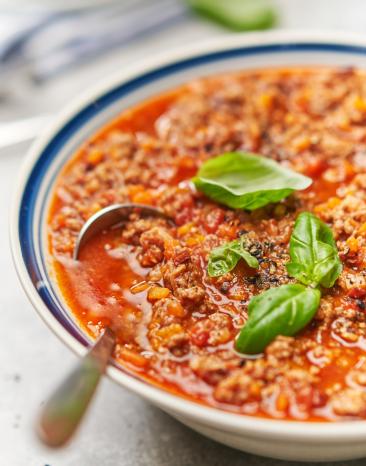 Sauce Ragout Bolognese mit Basilikum garniert in einer Schüssel. Sauce Ragout Bolognese mit Basilikum garniert in einer Schüssel.
