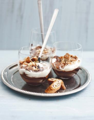 Schichtdessert mit Schokolade, Sahne und Cantuccinibroeseln in einem Glas.