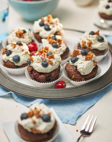 Viele Schoko-Muffins mit Früchten Chili und Sahnehaube auf einem Teller.