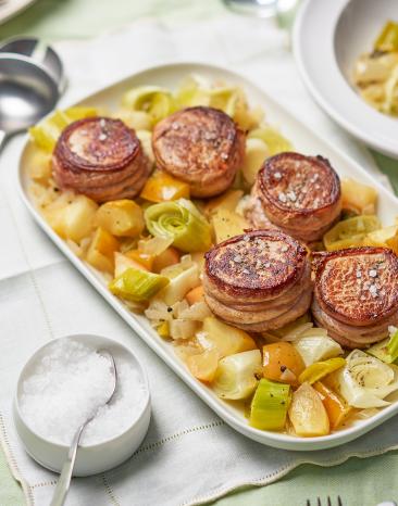 Schweinemedaillons auf Gemüse auf einer Servierplatte.