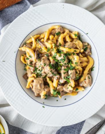 Schweinegeschnetzeltes mit Spätzle in Rahmsoße auf einem Teller angerichtet.