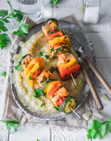Selleriepüree mit Lachs-Gemüse-Spießen auf einem Teller angerichtet.