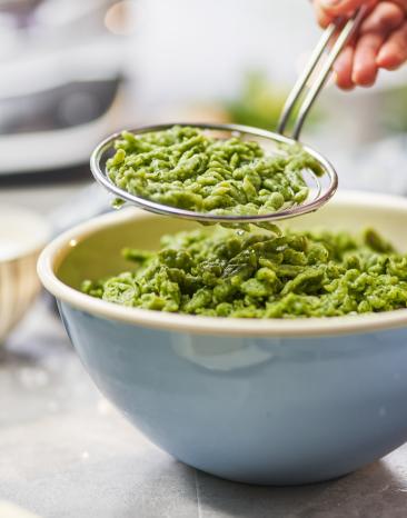 Spätzle grün werden mit einer Schaumkelle in eine Schüssel gegeben.