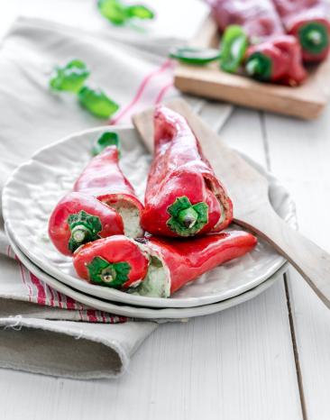 Drei gefüllte Spitzpaprikas auf einem Teller.