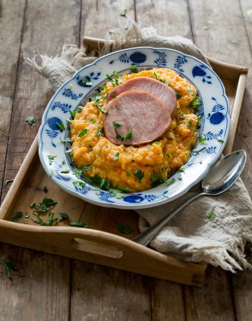 Steckrübenmus mit Kasseler auf einem Teller angerichtet.