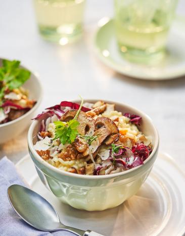 Steinpilz-Risotto mit karamellisierten Walnüssen in einer Schale angerichtet.