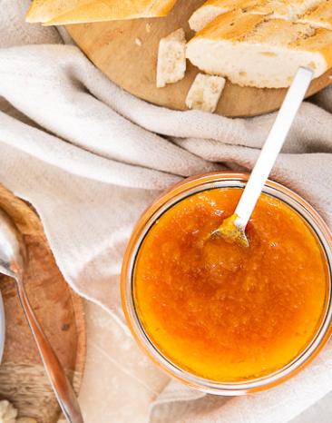 Süße Kürbismarmelade auf einem Brot neben Käse auf einer Platte.