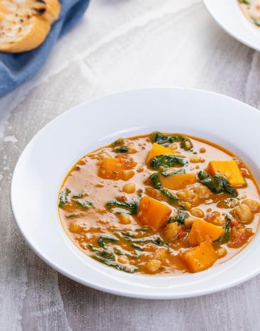 Süßkartoffel- und Kichererbsen-Curry mit Spinat auf Tellern.