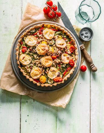 Vollkorn-Gemüse-Quiche mit Ziegenkäse auf einem Tisch.