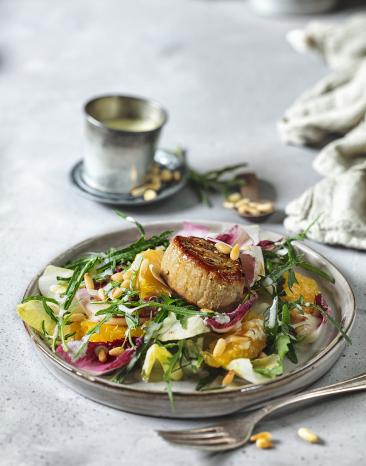 Wintersalat aus Chicorée und Orangen mit Schweinefiletmedaillons auf einem Teller.
