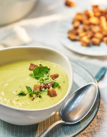 Zucchini-Kartoffel-Suppe in einem Teller mit Brotcroûtons garniert. Zucchini-Kartoffel-Suppe in einem Teller mit Brotcroûtons garniert.