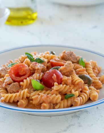 Pasta mit Thunfisch, Tomaten und Zitrone im tiefen Teller.